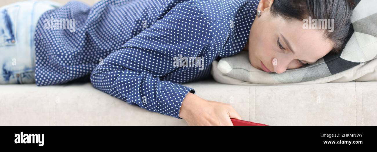 Donna triste si trova sul divano con smartphone primo piano Foto Stock