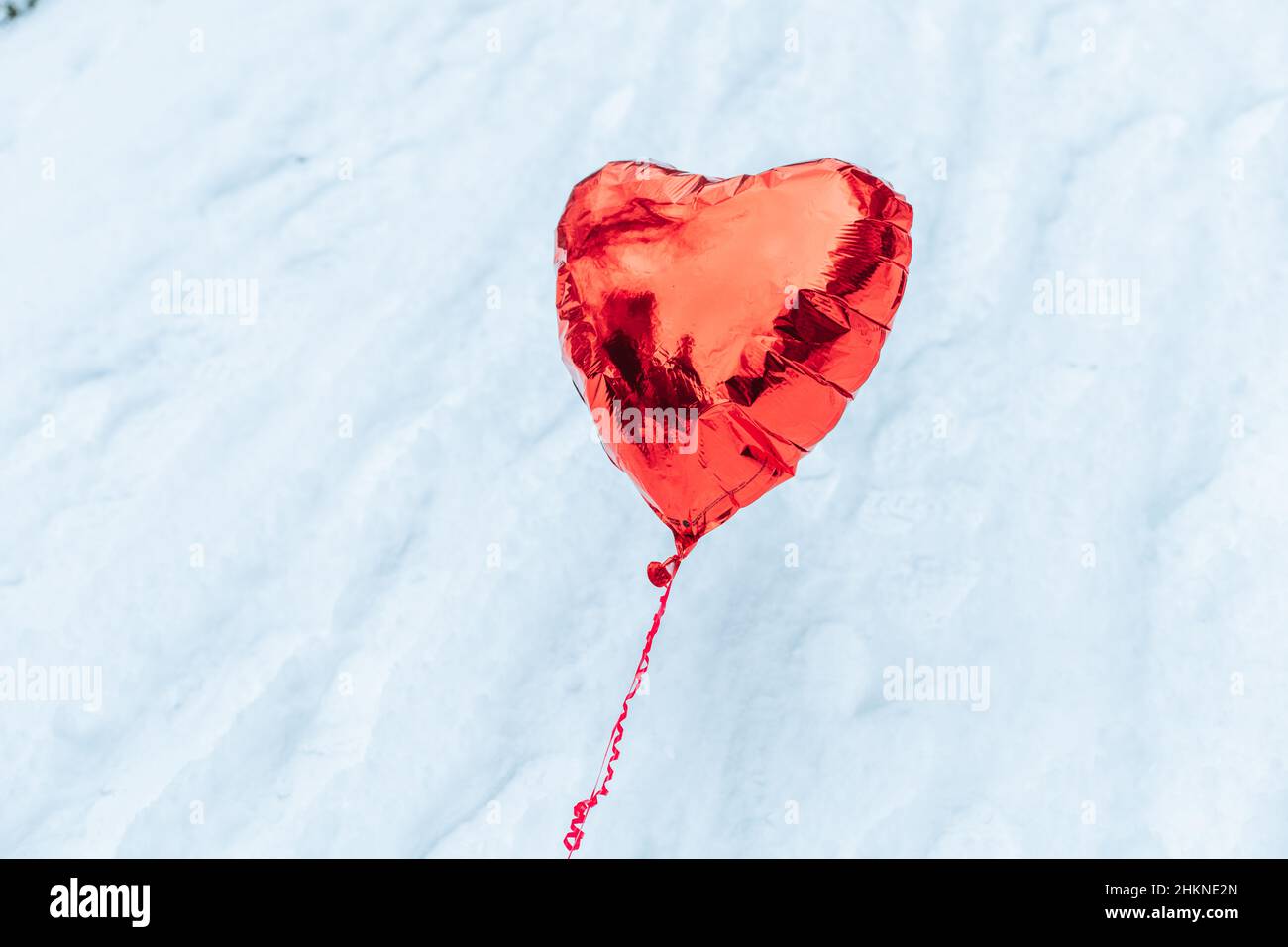 Mongolfiera di elio a cuore rosso sopra la neve. San Valentino Foto Stock