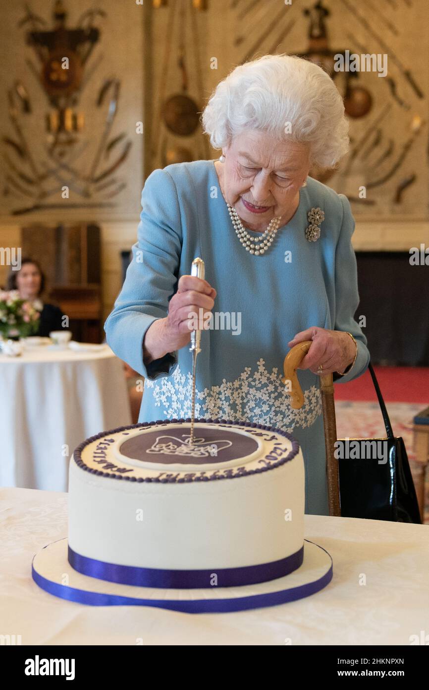 La Regina Elisabetta II taglia una torta per celebrare l'inizio del Giubileo del platino durante un ricevimento nella Sala da ballo di Sandringham House, che è la residenza della Regina Norfolk. Data foto: Sabato 5 febbraio 2022. Foto Stock