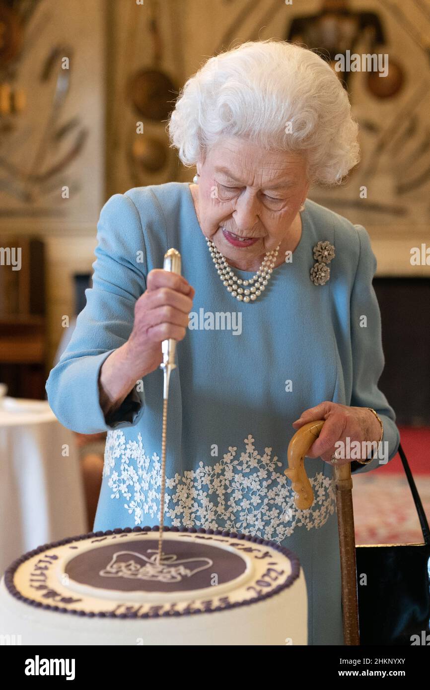 La Regina Elisabetta II taglia una torta per celebrare l'inizio del Giubileo del platino durante un ricevimento nella Sala da ballo di Sandringham House, che è la residenza della Regina Norfolk. Data foto: Sabato 5 febbraio 2022. Foto Stock