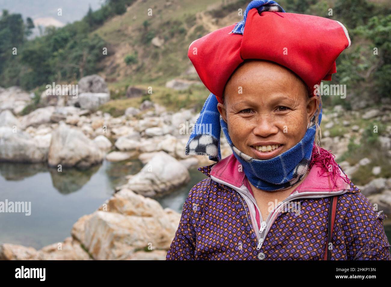 Allegro rosso Dao etnia minoritaria donna con copricapo tipico e sorridente vicino a Sapa, Lao Cai, Vietnam. Foto Stock