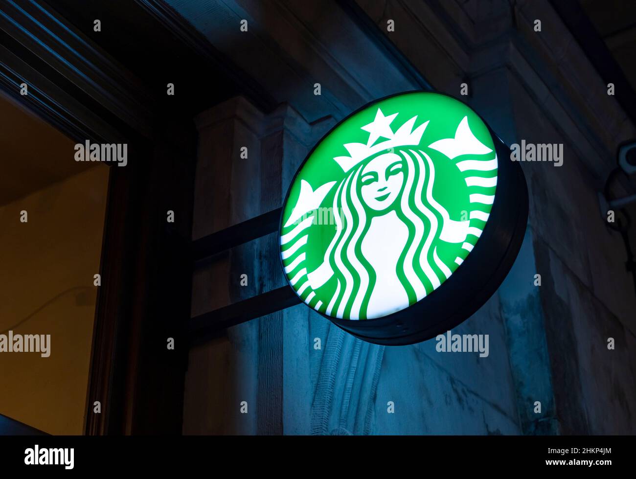 Starbucks Coffee Round cafe cartello con il logo di notte, luminoso cartello con il logo primo piano, segnaletica dettagliata, nessuno. La più grande catena di caffè del mondo Foto Stock