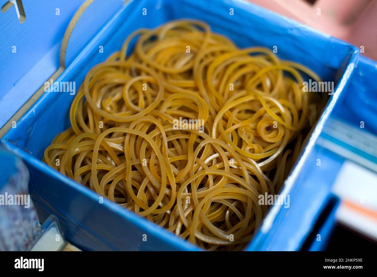 Pila di elastici gialli in un contenitore blu Foto Stock