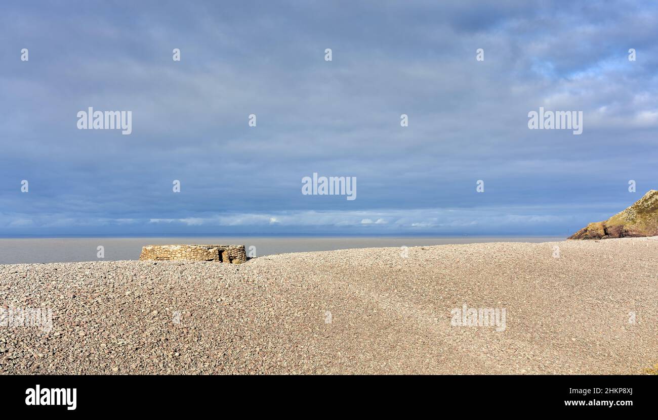 La scatola della pillola WWII sulla cresta di ghiaia e masso di Bossington Beach in Exmoor National Park Somerset UK quasi sepolto dalla barriera avanzante Foto Stock