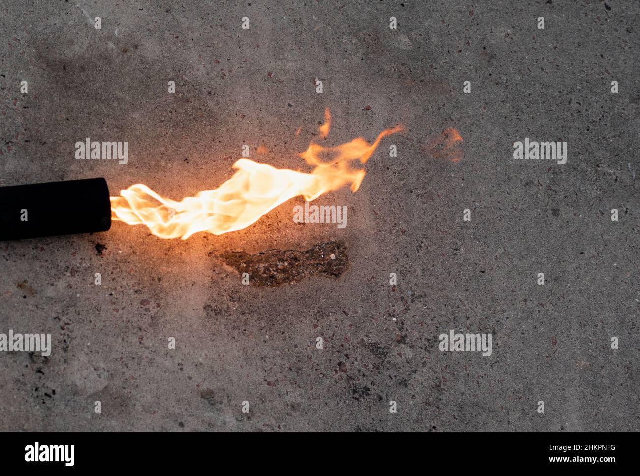 Fiamma lunga di un bruciatore a gas su sfondo di cemento grigio Foto Stock