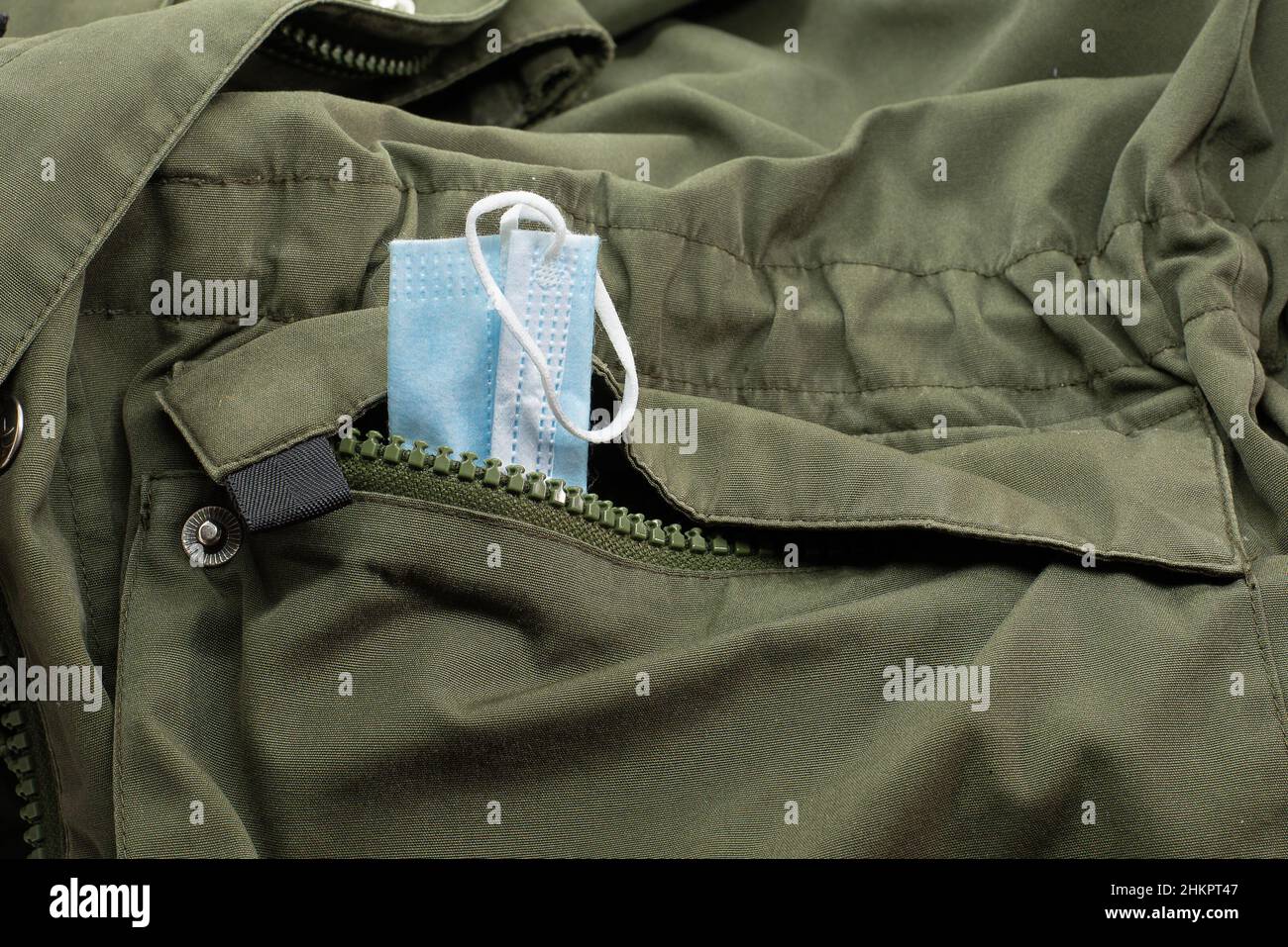 Maschera blu in una tasca con zip di una giacca verde, Frederikssund, Danimarca, 4 febbraio 2022 Foto Stock