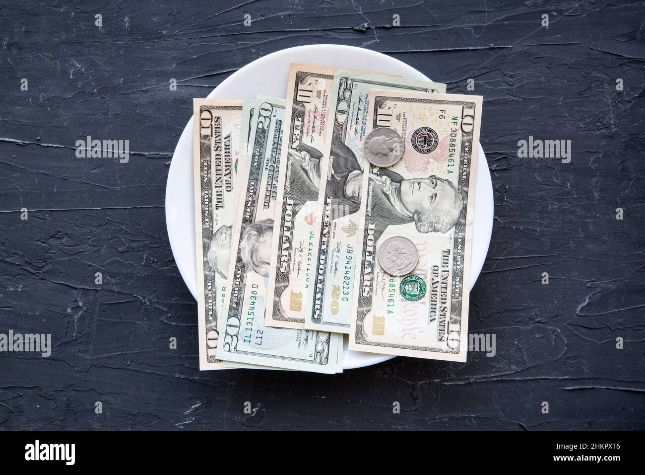Denaro speso per il concetto di cibo sul backgorund nero negli Stati Uniti. Dollari nel piatto. Foto Stock