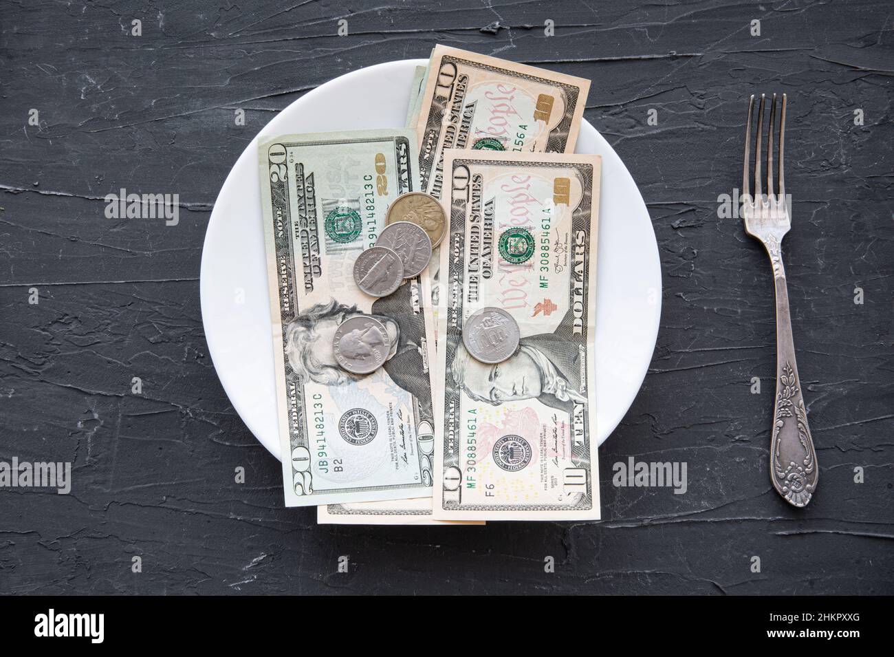 Denaro speso per il concetto di cibo sul backgorund nero negli Stati Uniti. Dollari nel piatto. Foto Stock