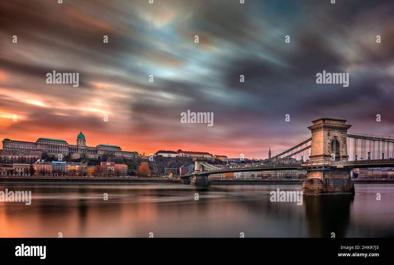 Budapest, Ungheria - Ponte delle catene Szechenyi e Palazzo reale del Castello di Buda con il cielo e le nuvole colorate al tramonto in un pomeriggio d'inverno Foto Stock