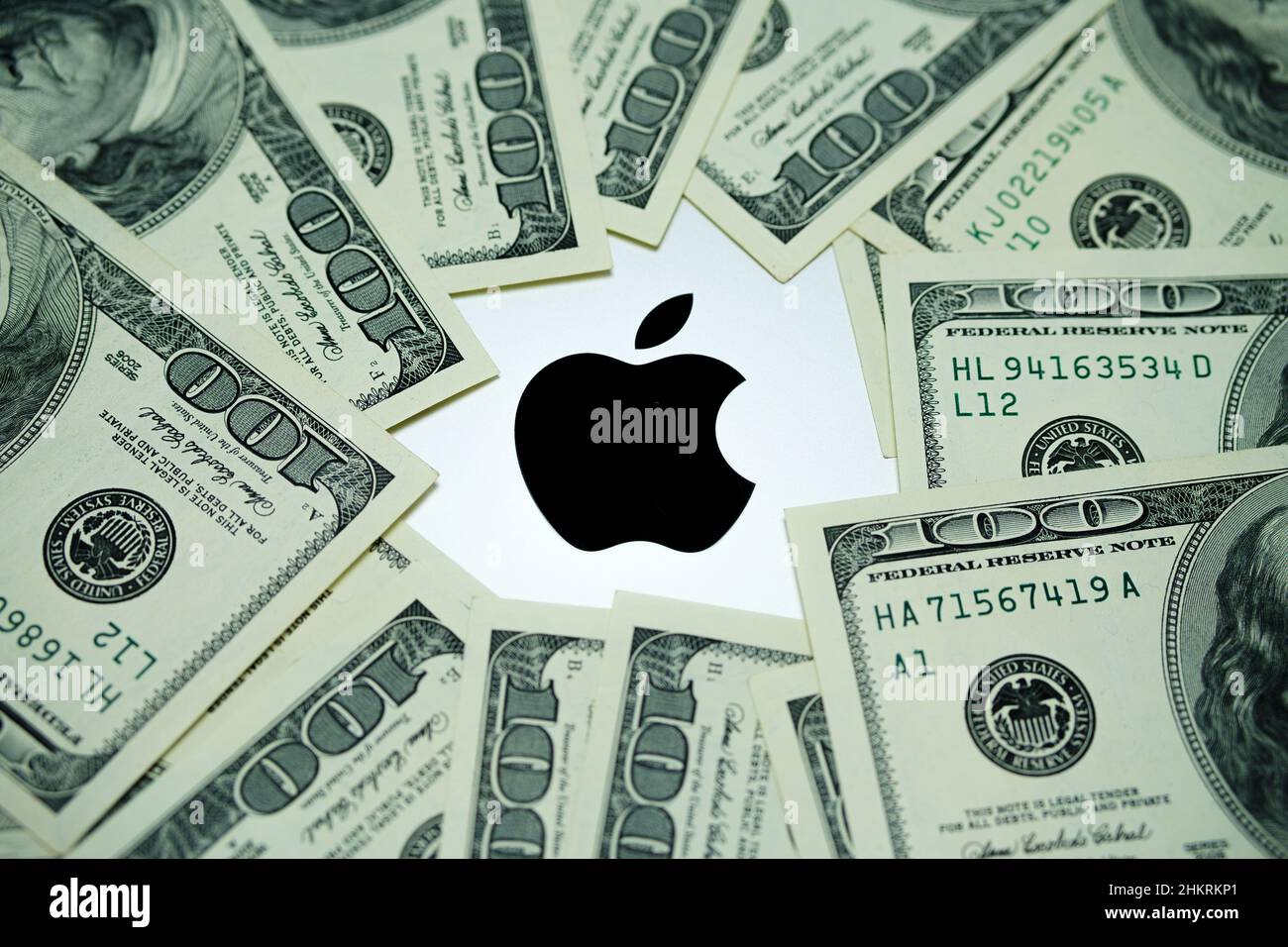Logo Apple Company visto sul laptop MacBook M1 circondato da banconote in dollari statunitensi. Concetto. Messa a fuoco selettiva. Regno Unito, Stafford, 18 dicembre 2021. Foto Stock