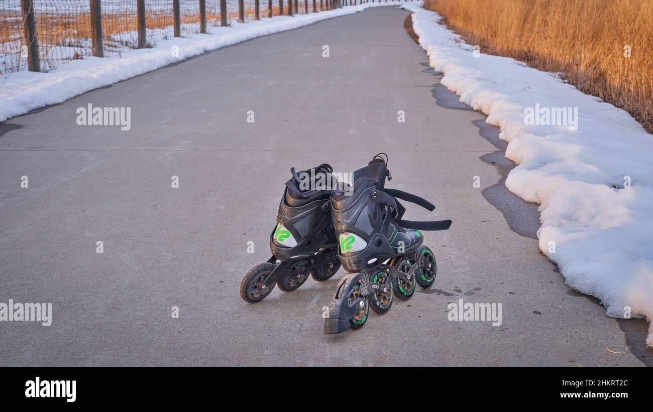 Loveland, CO, USA - 17 gennaio 2022: Un paio di pattini in linea sporchi (K2 MOD 110 Speed Lace) con ruote da 110 mm dopo aver pattinato su una pista ciclabile bagnata in wi Foto Stock