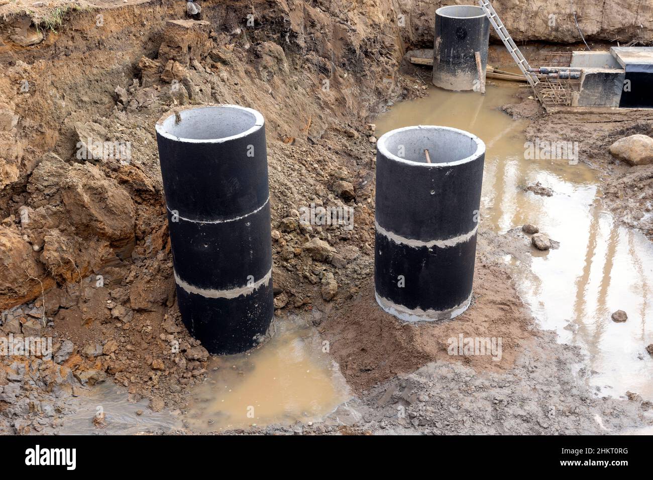 Costruzione anelli in calcestruzzo sul cantiere, un sistema di comunicazione sotterranea con un nuovo edificio residenziale sul cantiere. L Foto Stock