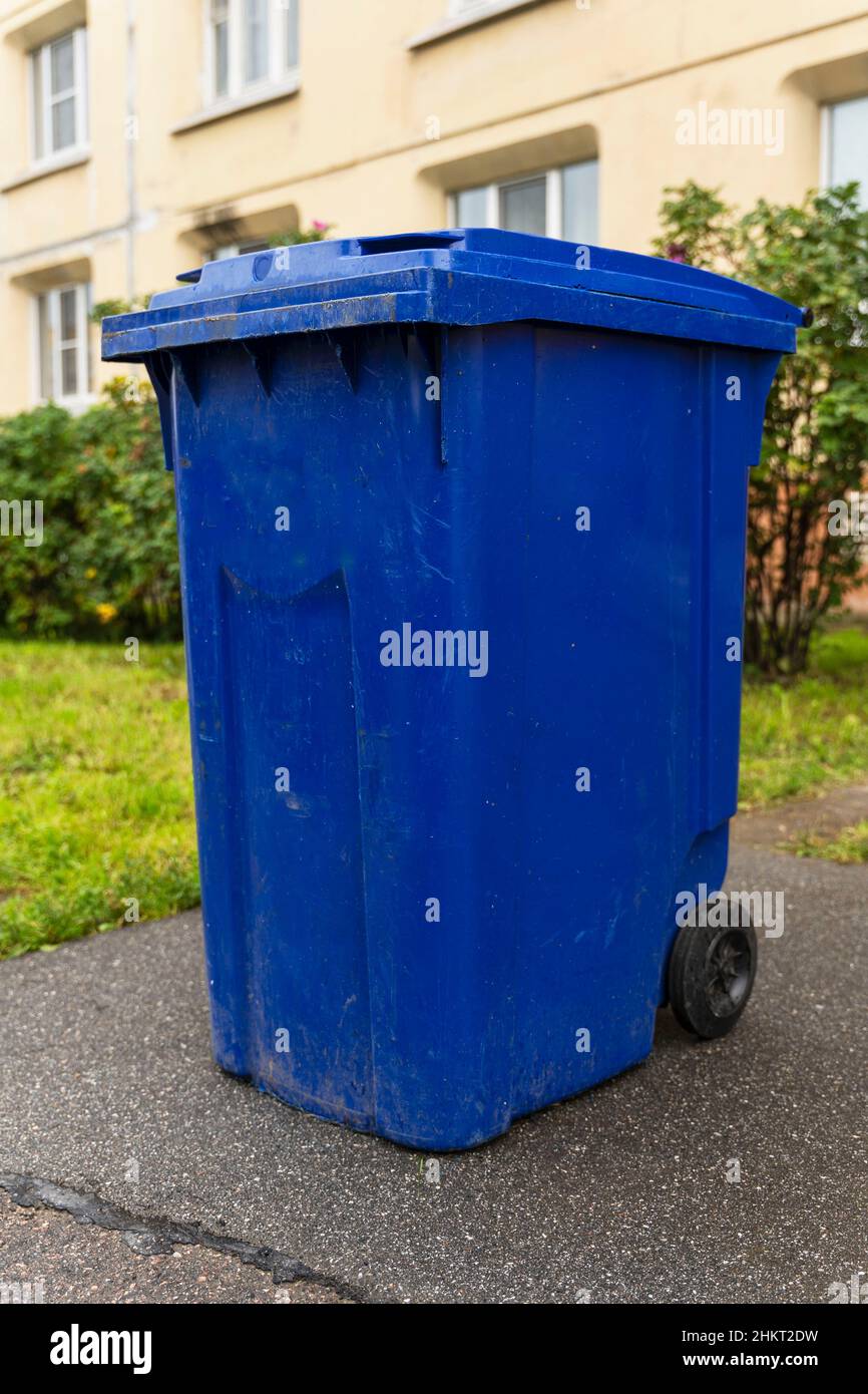 Contenitore di rifiuti blu in plastica nel cortile di un edificio residenziale. Foto Stock