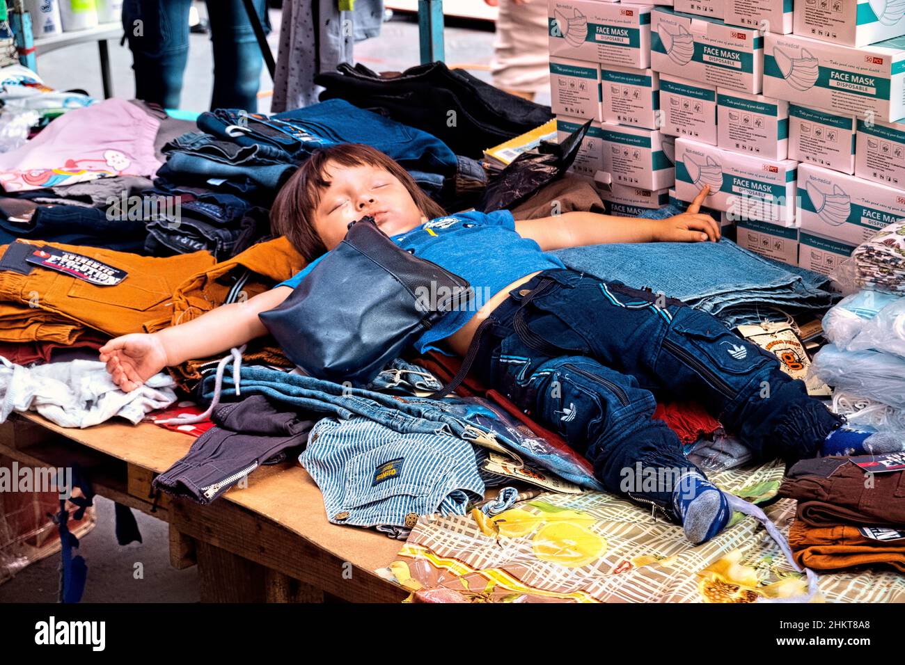 Ragazzo suono addormentato nel mercato dell'abbigliamento, San Salvador, El Salvador Foto Stock