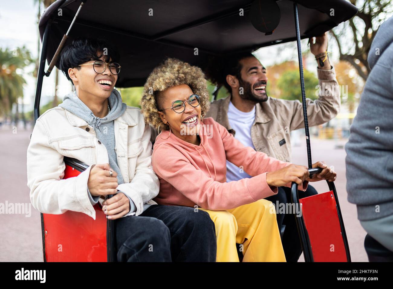 Tre allegri amici turistici diversi che cavalcano in tuk tuk taxi in vacanza Foto Stock