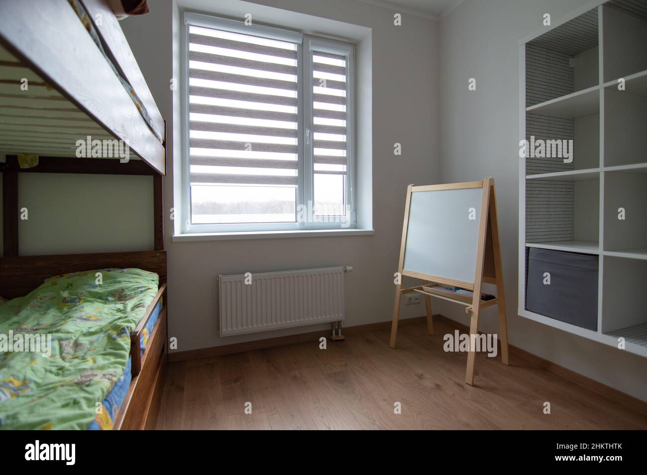 Camera per bambini in un appartamento con letto a due piani, un set di ripiani e una lavagna bianca Foto Stock