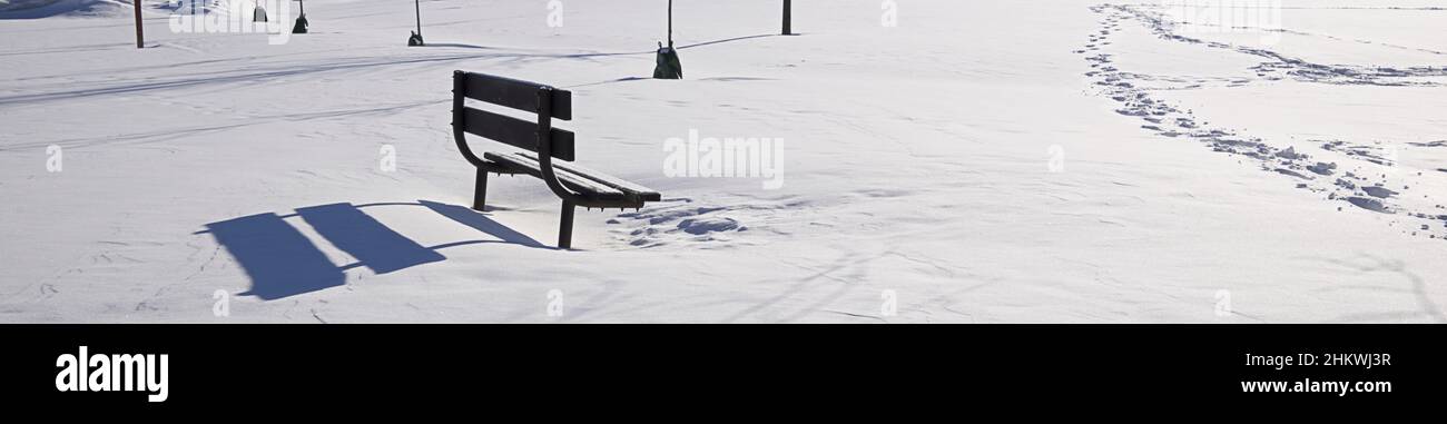 Foto panoramica di una panchina del parco coperta di neve profonda nel parco. Sfondo formato orizzontale. Foto Stock