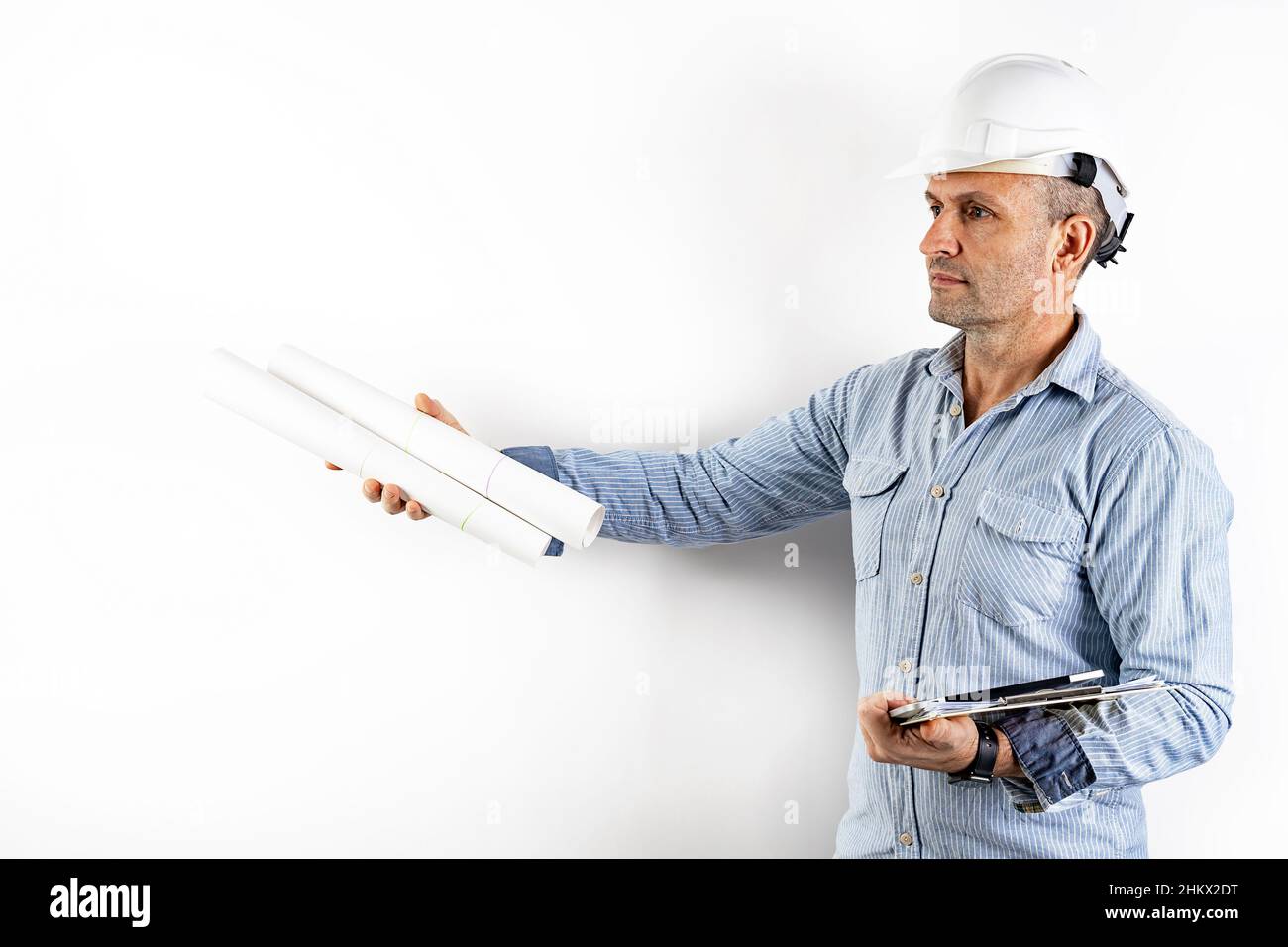 Ingegnere civile maschile di mezza età con blueprint nelle mani e con un casco bianco rigido. Ritratto isolato su sfondo bianco. Materiale maschio ph Foto Stock