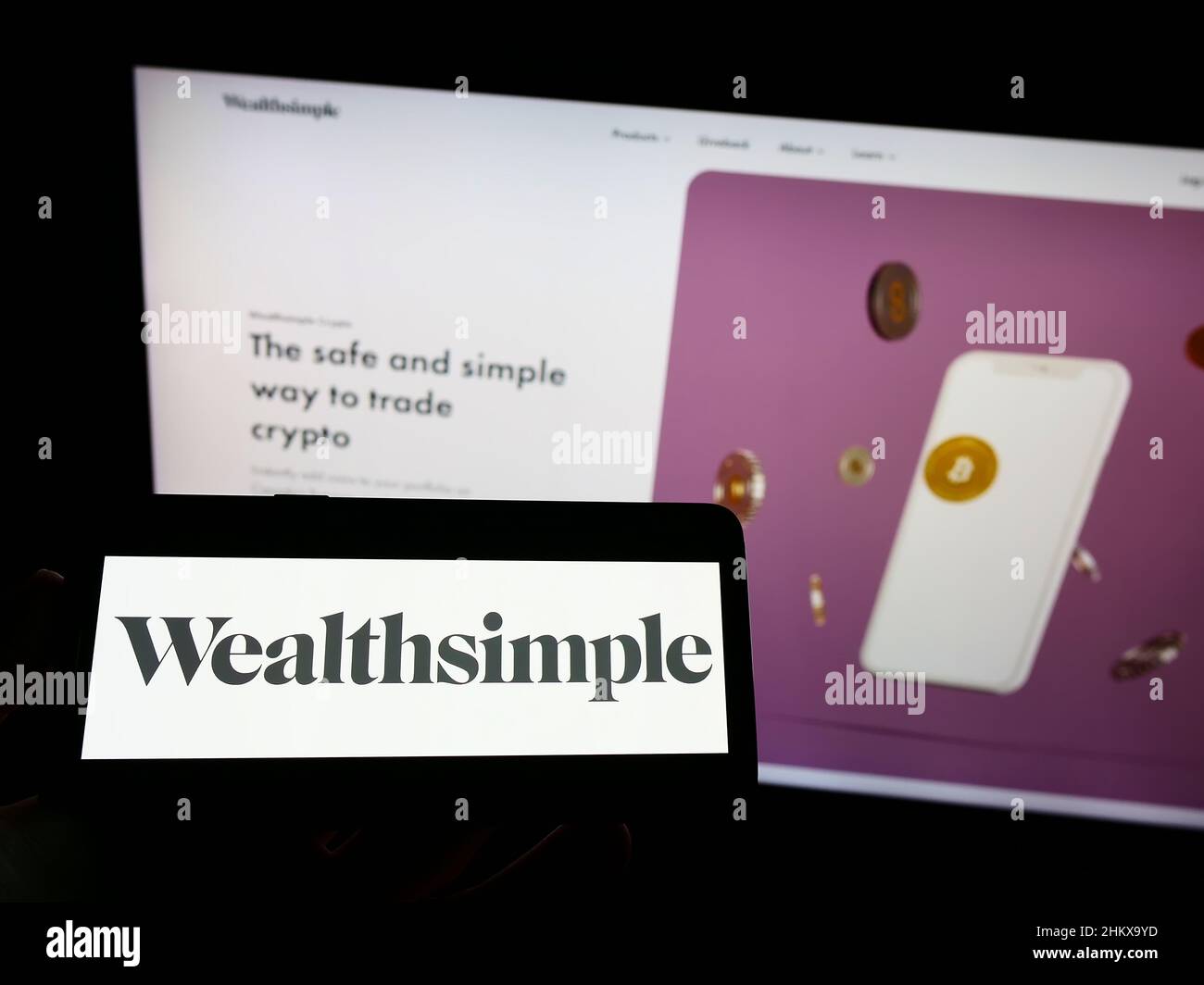 Persona che tiene il cellulare con il logo della società canadese di servizi finanziari Wealthsimple sullo schermo di fronte al sito web. Mettere a fuoco sul display del telefono. Foto Stock