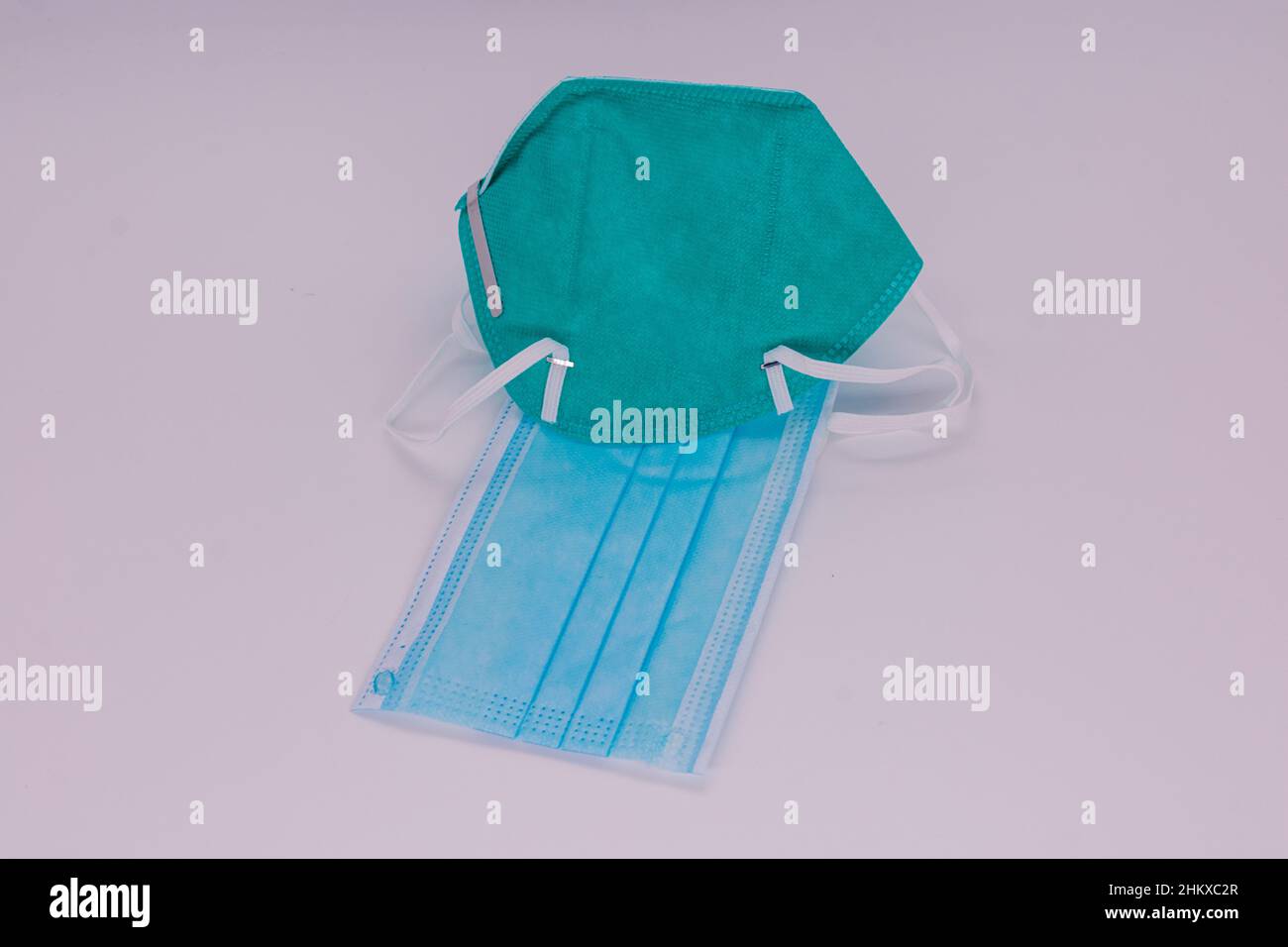 Una maschera chirurgica blu e un respiratore medico di protezione N-95 isolato su sfondo bianco. Foto Stock