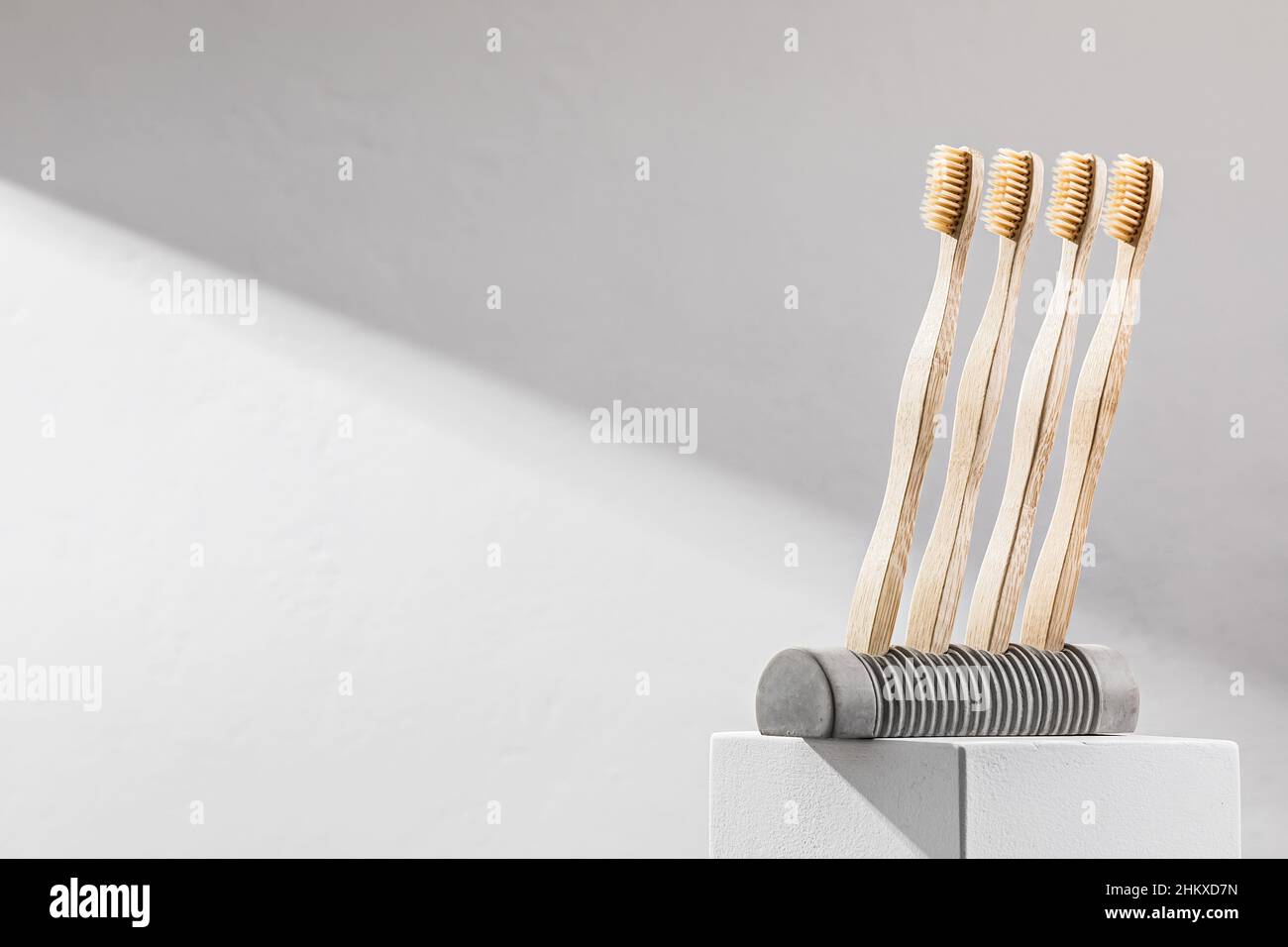 Spazzolini da denti in legno in un supporto in calcestruzzo. Concetto ecologico Foto Stock