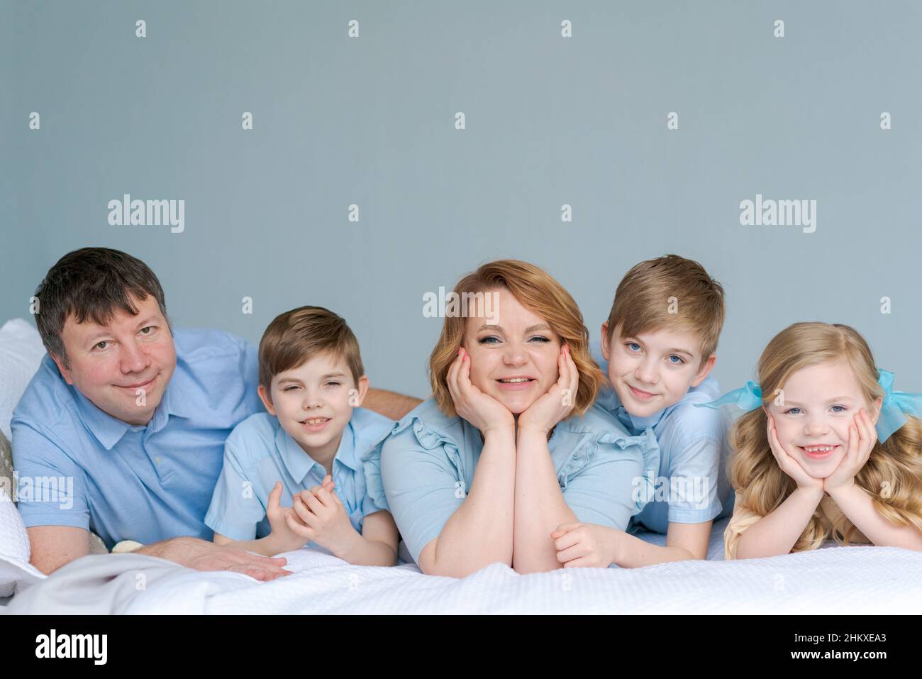 Felice famiglia caucasica si trovano in camera da letto e sorridere. Vestiti di blu stanno divertendosi insieme. Genitori e figli due figli e una figlia carina Foto Stock