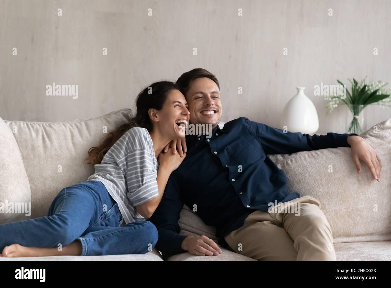 L'uomo e la donna sognanti eccitati abbracciano, sedendosi rilassandosi sul divano Foto Stock