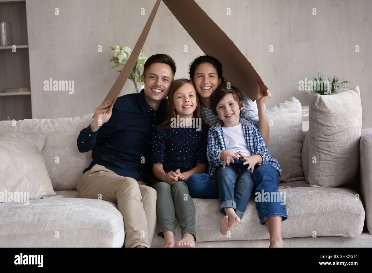 Ritratto di famiglia sorridente genitori con bambini seduti sotto il tetto di cartone Foto Stock