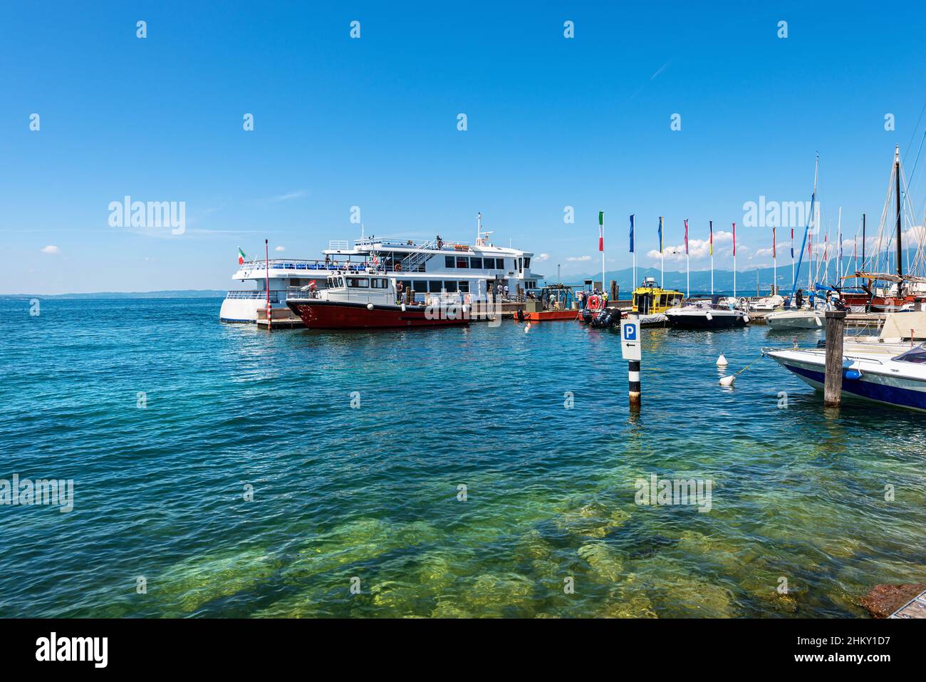 Piccolo porto e stazione dei traghetti del villaggio di Bardolino con molte piccole barche ormeggiate. Località turistica sulla costa del Lago di Garda. Verona, Italia. Foto Stock