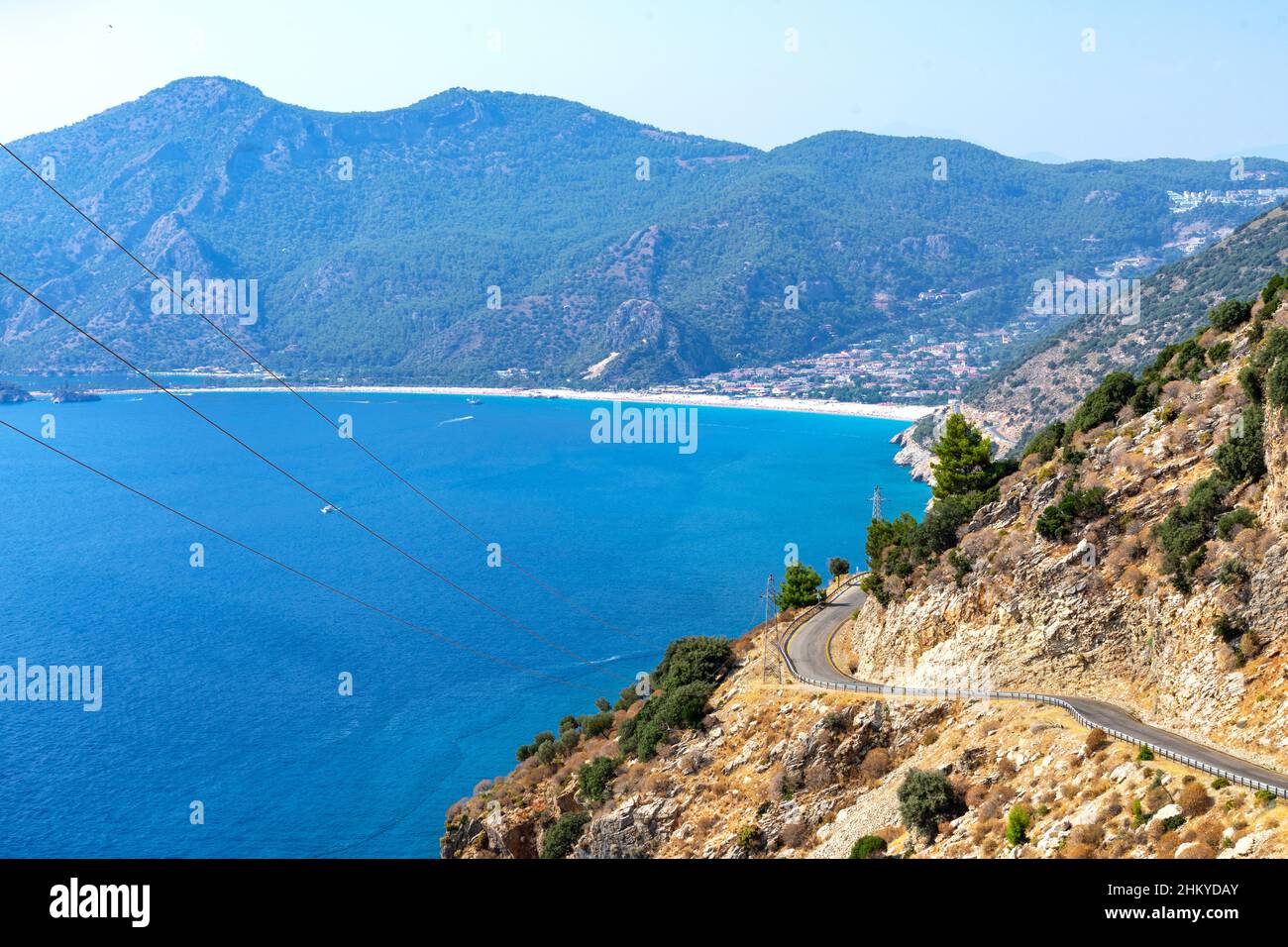 Curva curvilinea di strada di montagna con cielo blu e mare sullo sfondo. Fethiye Oludeniz spiaggia vista dalla collina. La spiaggia di Oludeniz è una delle più bea Foto Stock