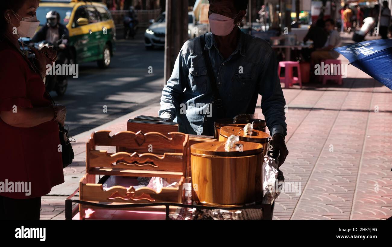 Uomo che vende articoli per la casa in legno da un carrello a spinta sul passaggio pedonale di Sukhumvit Road Bangkok Thailandia Foto Stock