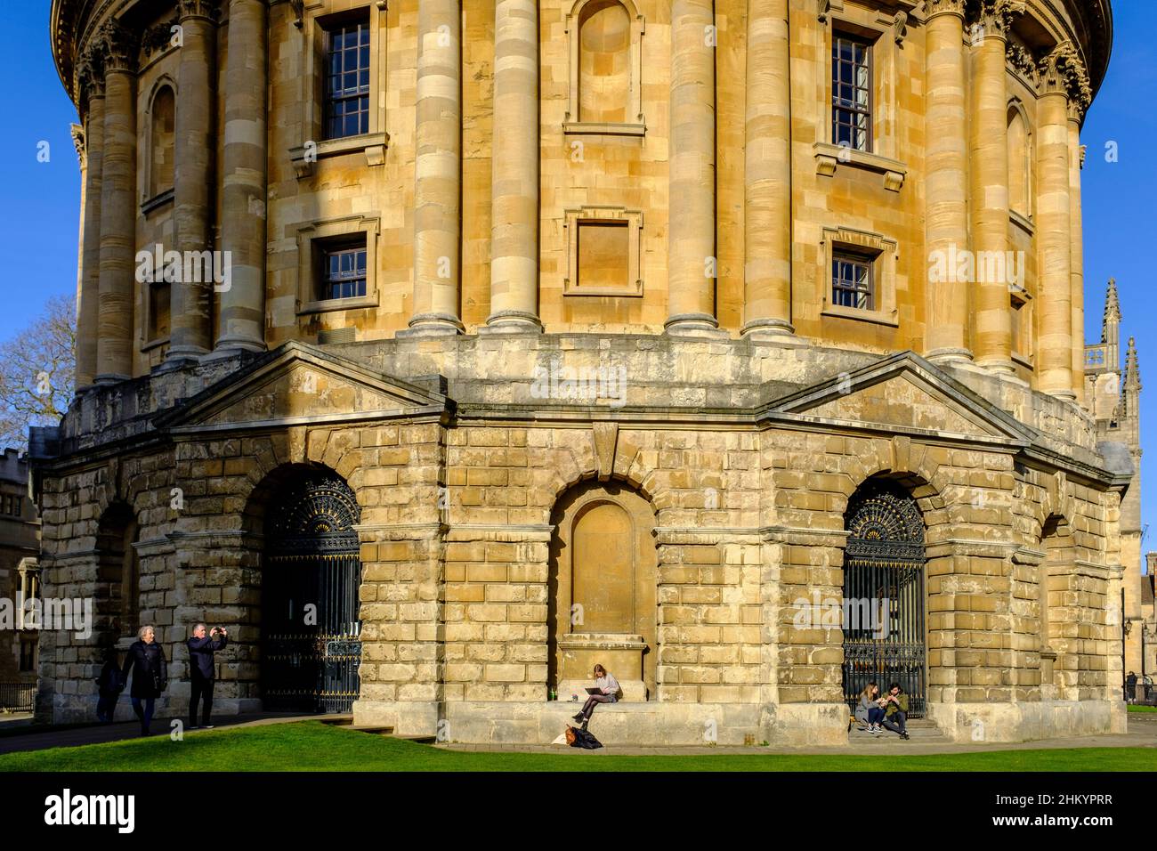 Uno studente seduto su una sporgenza della finestra al sole della mattina presto alla Bodleian Library a Oxford, Regno Unito Foto Stock