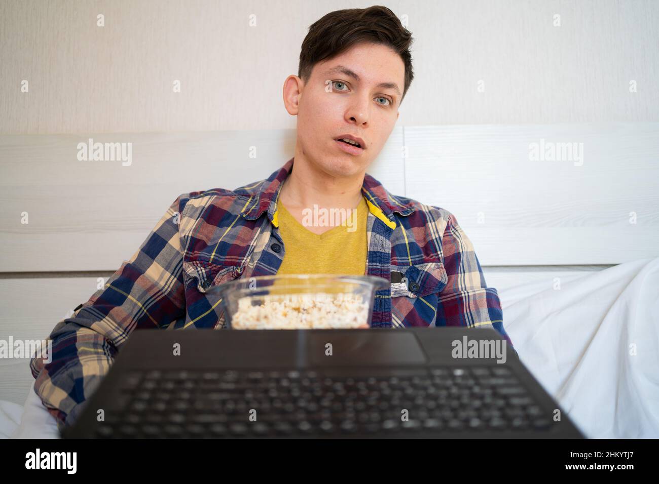 Ritratto di uomo caucasico in abiti casual sdraiati a casa, guardando lo schermo del laptop con espressione stupita, guardando contenuti scioccanti, sorpresa Foto Stock