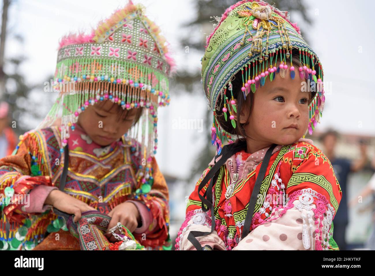 Ragazze giovani, indossando abiti tradizionali della tribù Hmong, aspettano di posare per le fotografie dei turisti nella piazza della città, Sapa (SA Pa), Lao Cai, Vietnam Foto Stock