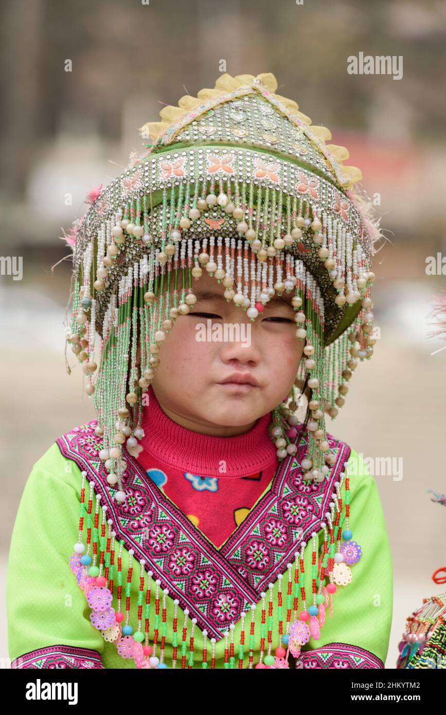 Una giovane ragazza, indossando abiti tradizionali della tribù Hmong, aspetta di posare per le fotografie dei turisti nella piazza della città, Sapa (SA Pa), Lao Cai, Vietnam Foto Stock