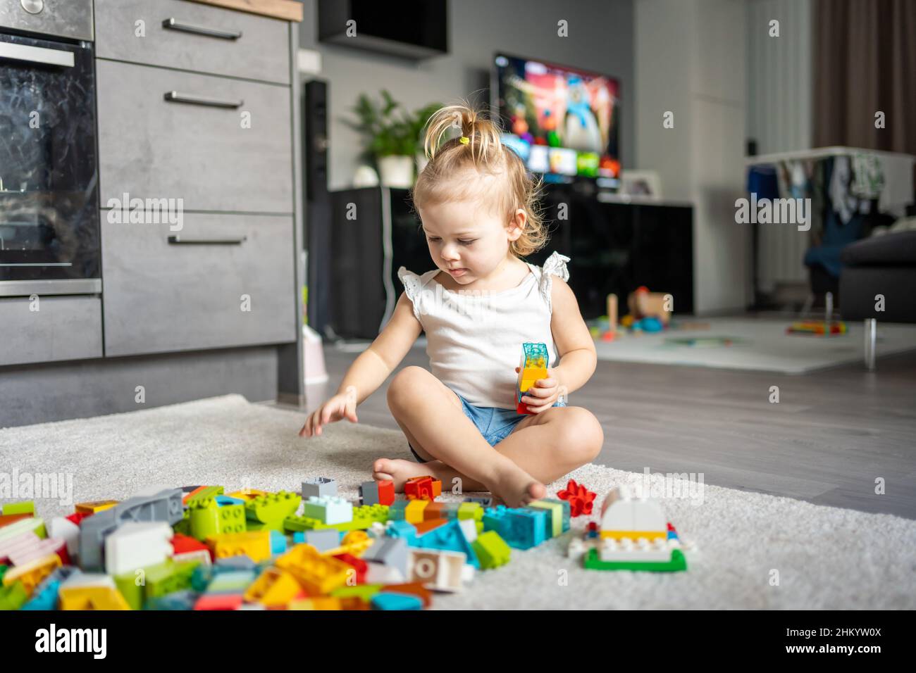 Bambino caucasico una bambina sta giocando nel costruttore a casa. Giocattoli educativi per bambini. Foto Stock