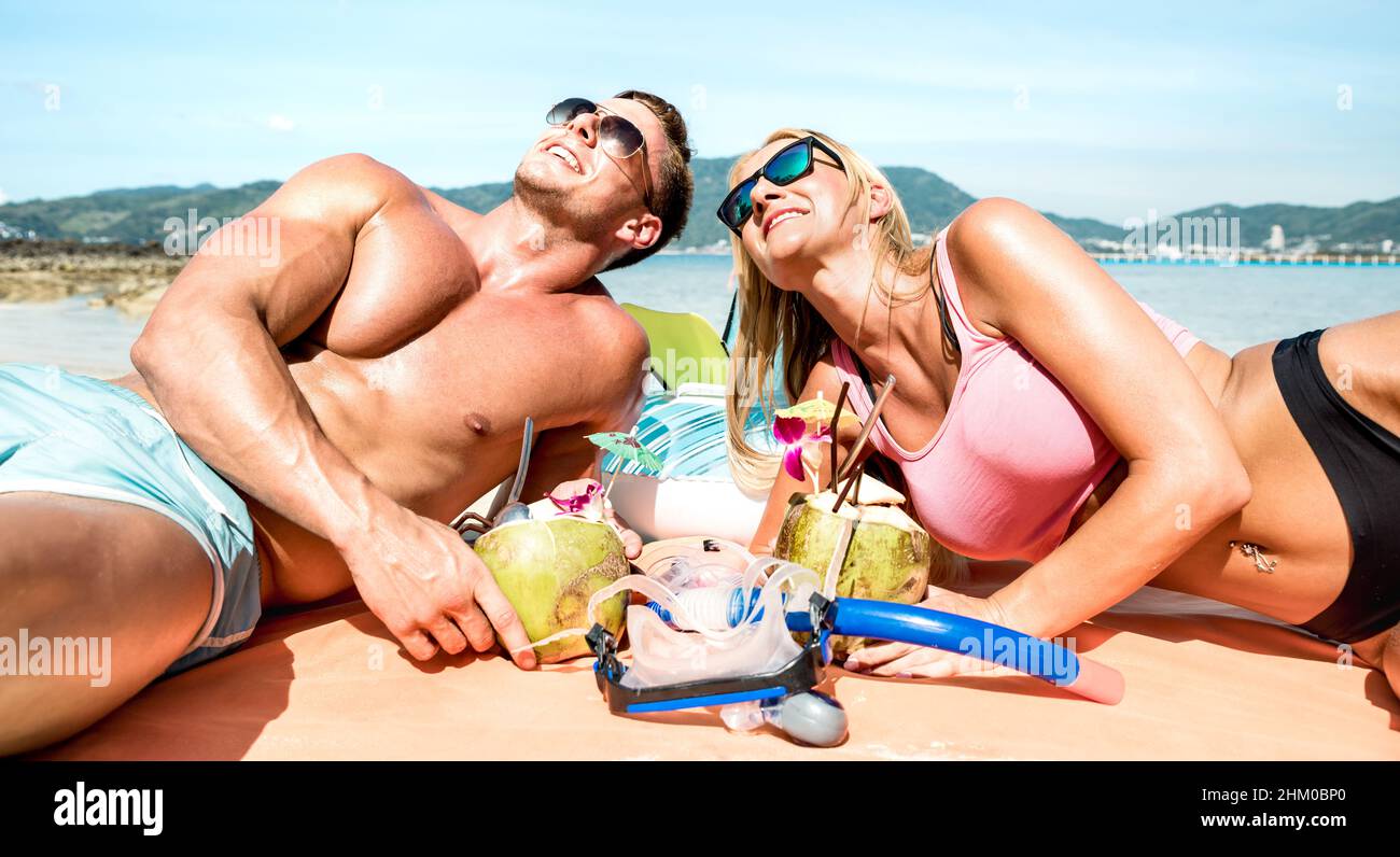 I giovani viaggiatori di coppia bevono cocktail di cocunut e si divertono sulla spiaggia tropicale - concetto di lusso stile di vita con influencer di moda che viaggiano aroun Foto Stock