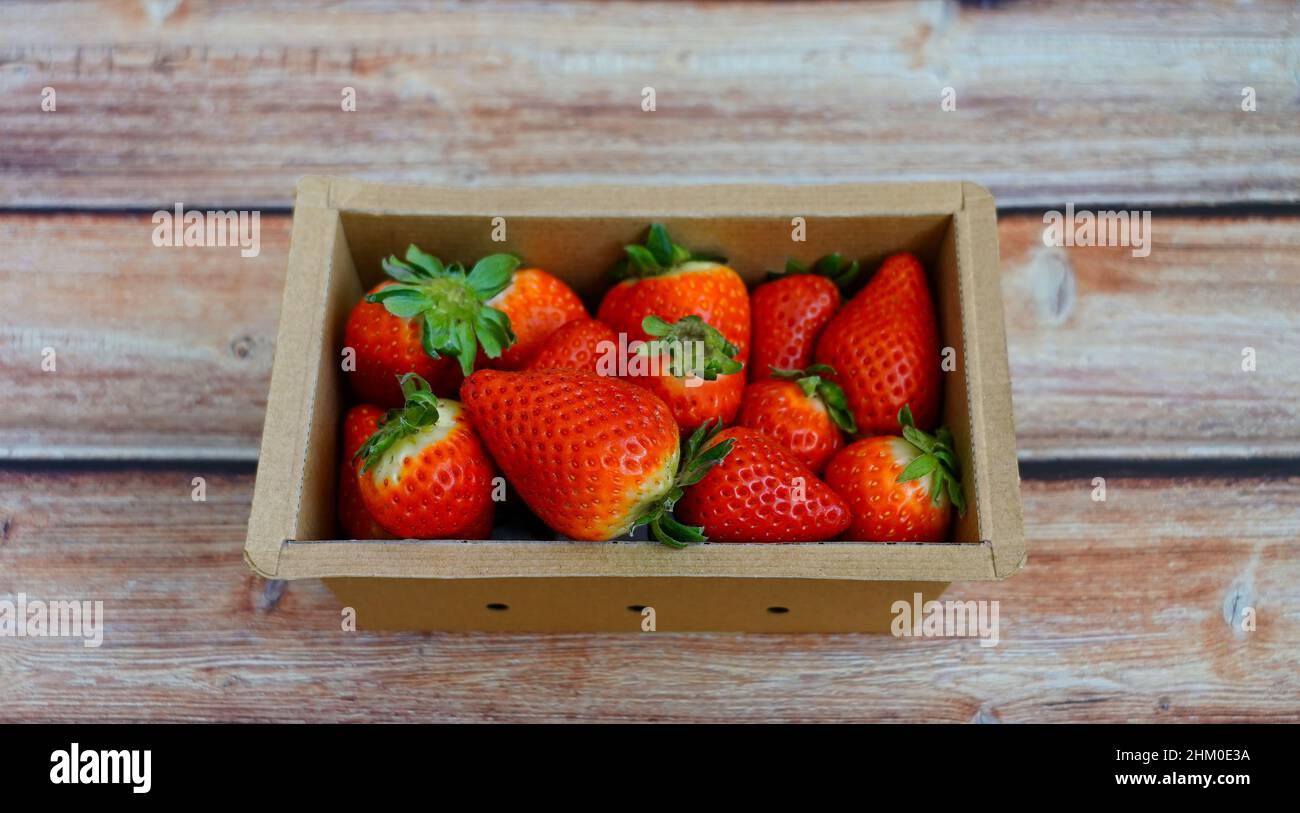 Primo piano di fragole biologiche succose in una scatola di cartone ecologica. Foto Stock