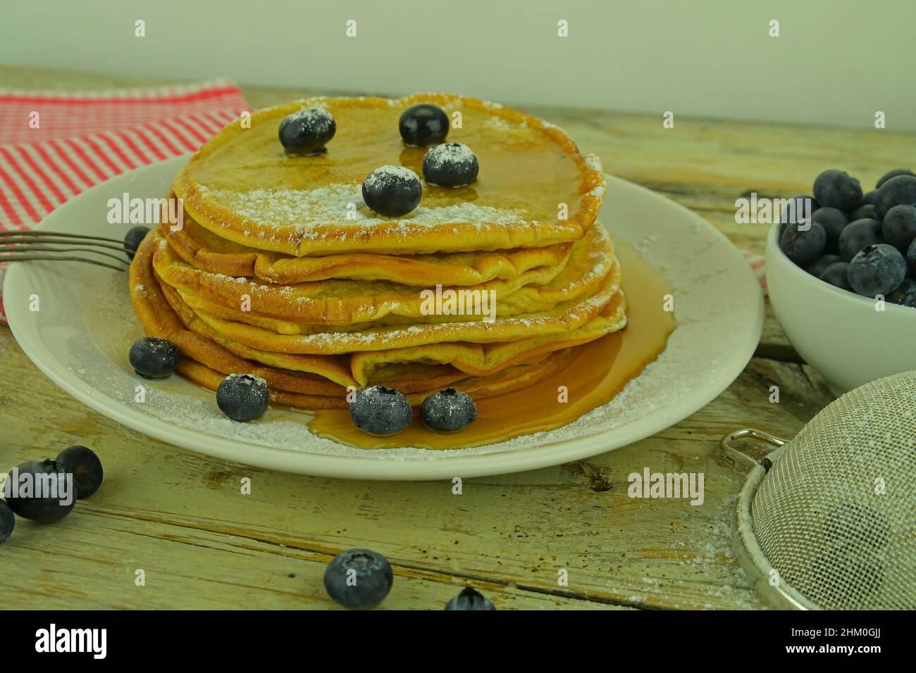 Pancake americani fatti in casa con mirtilli freschi e sciroppo d'acero. Colazione sana. Sfondo bianco rustico. Pancake con frutti di bosco su legno bianco Foto Stock