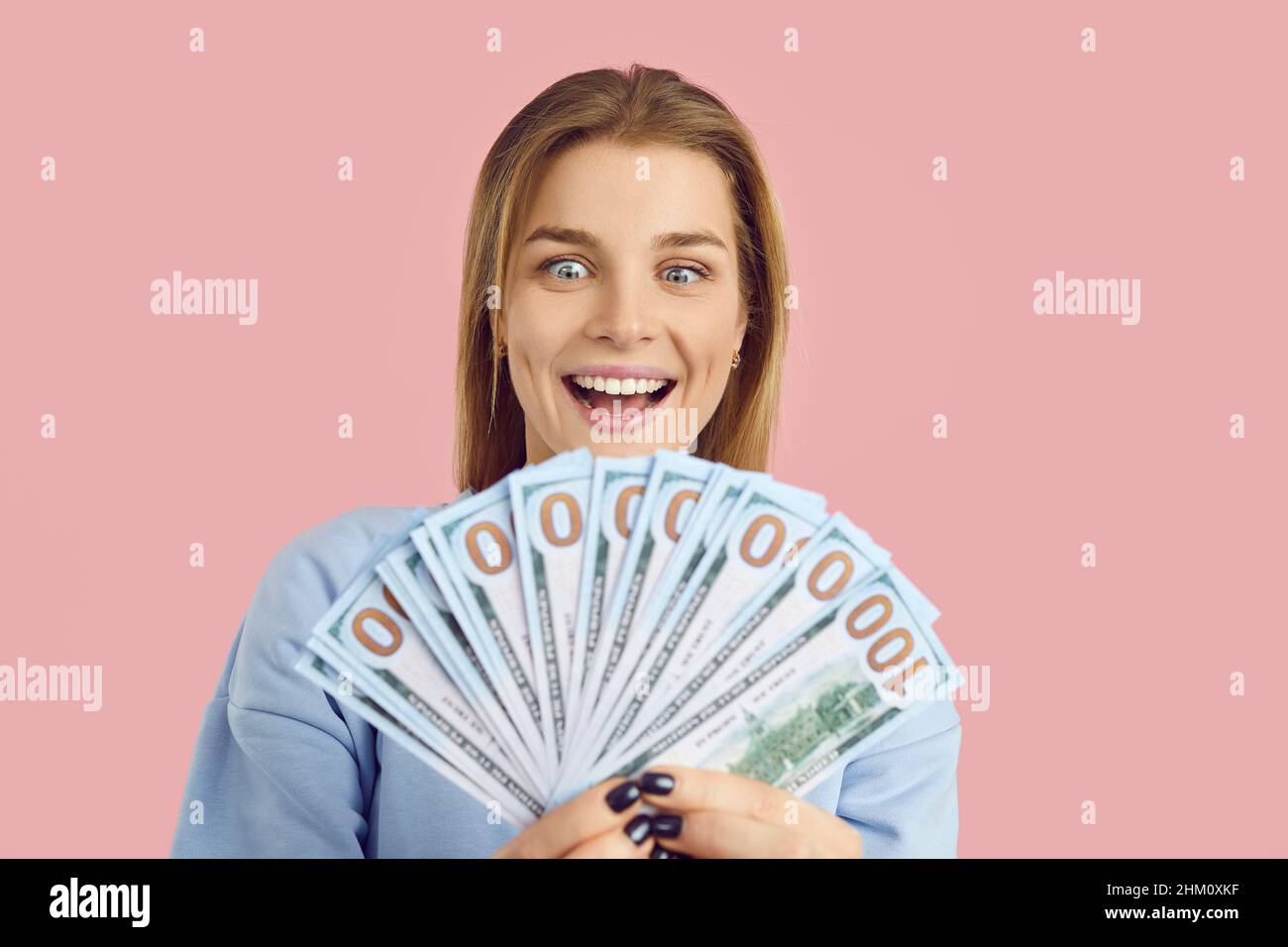 Felice sorpresa giovane donna che detiene premio in denaro che ha vinto in lotteria e sorridente Foto Stock