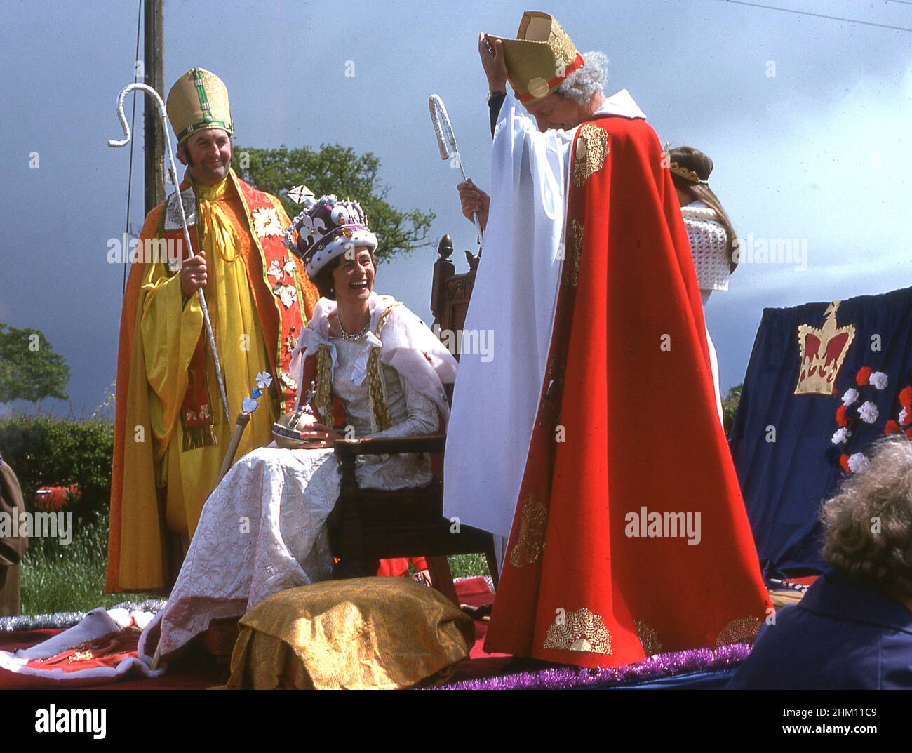 1977, storica, sul retro di un trattore, una sfilata galleggiante con una donna e due uomini vestiti in costume come sacerdoti e la regina che celebra il giubileo d'argento della regina Elisabetta II, Inghilterra, Regno Unito. Foto Stock