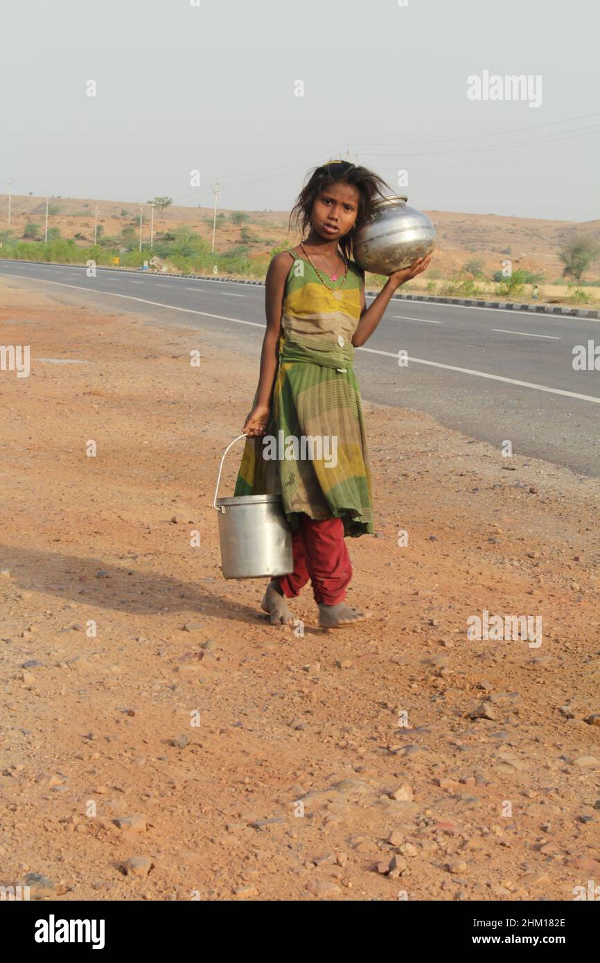 Una giovane ragazza che cammina a casa con vasi d'acqua in un villaggio rurale. Javadhu Hills, Tamil Nadu. India. Foto Stock