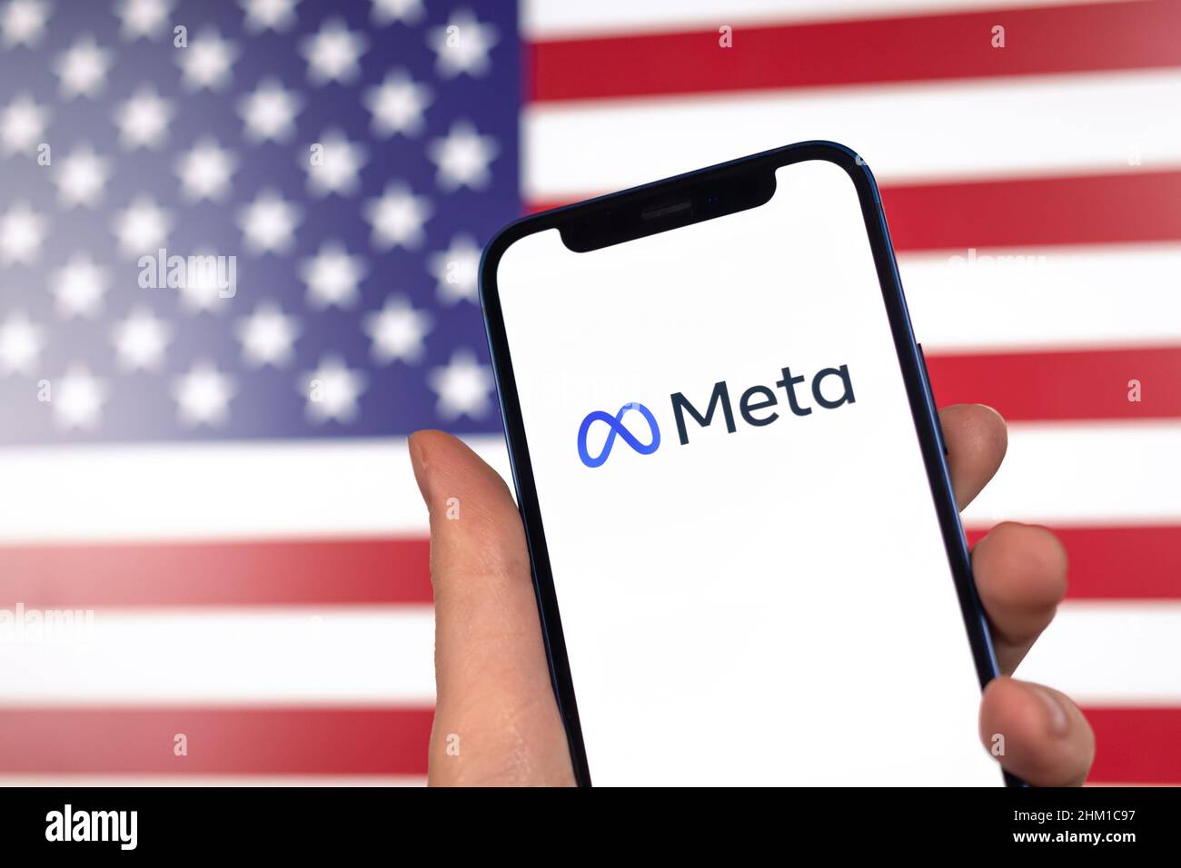 Meta logo e bandiera americana sullo sfondo. La metaversa Facebook e gli Stati Uniti. Mano con il telefono cellulare Foto Stock