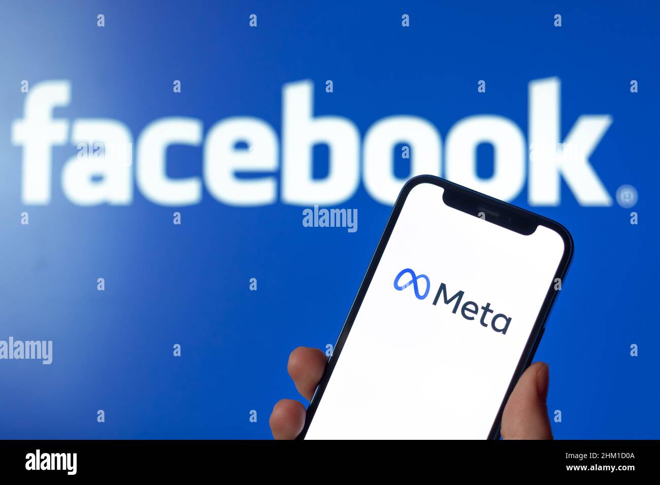 Logo Facebook e Meta. Mano con il telefono cellulare Foto Stock