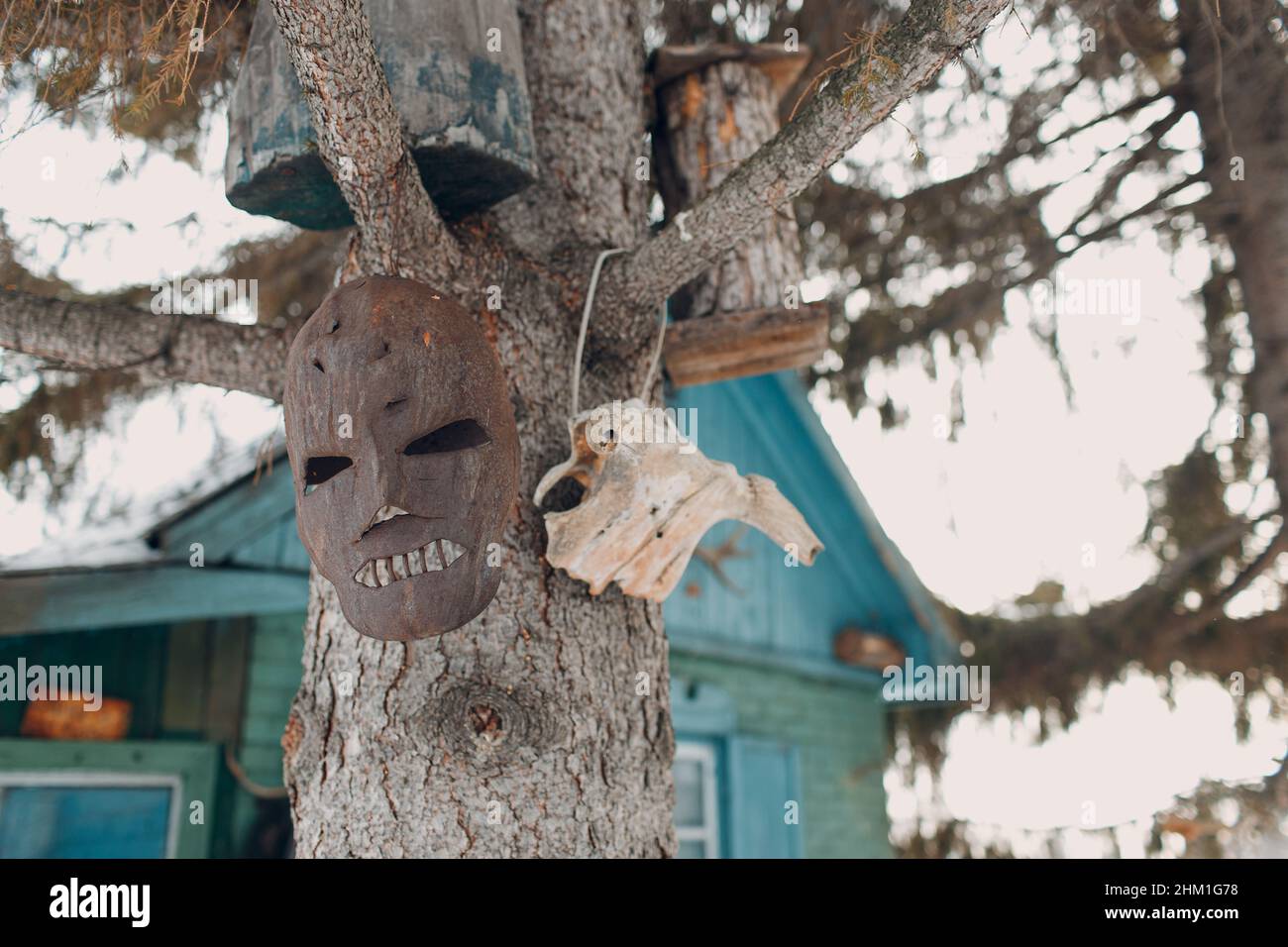 Vecchia maschera di maniaco di metallo arrugginita appesa all'albero Foto Stock
