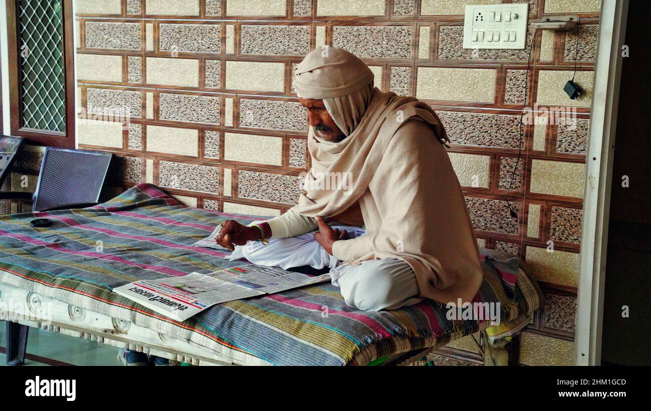 30 gennaio 2022 Reengus, Rajasthan, India. L'uomo indiano non identificato invecchiato siede confortevolmente e legge il giornale indiano. Foto Stock