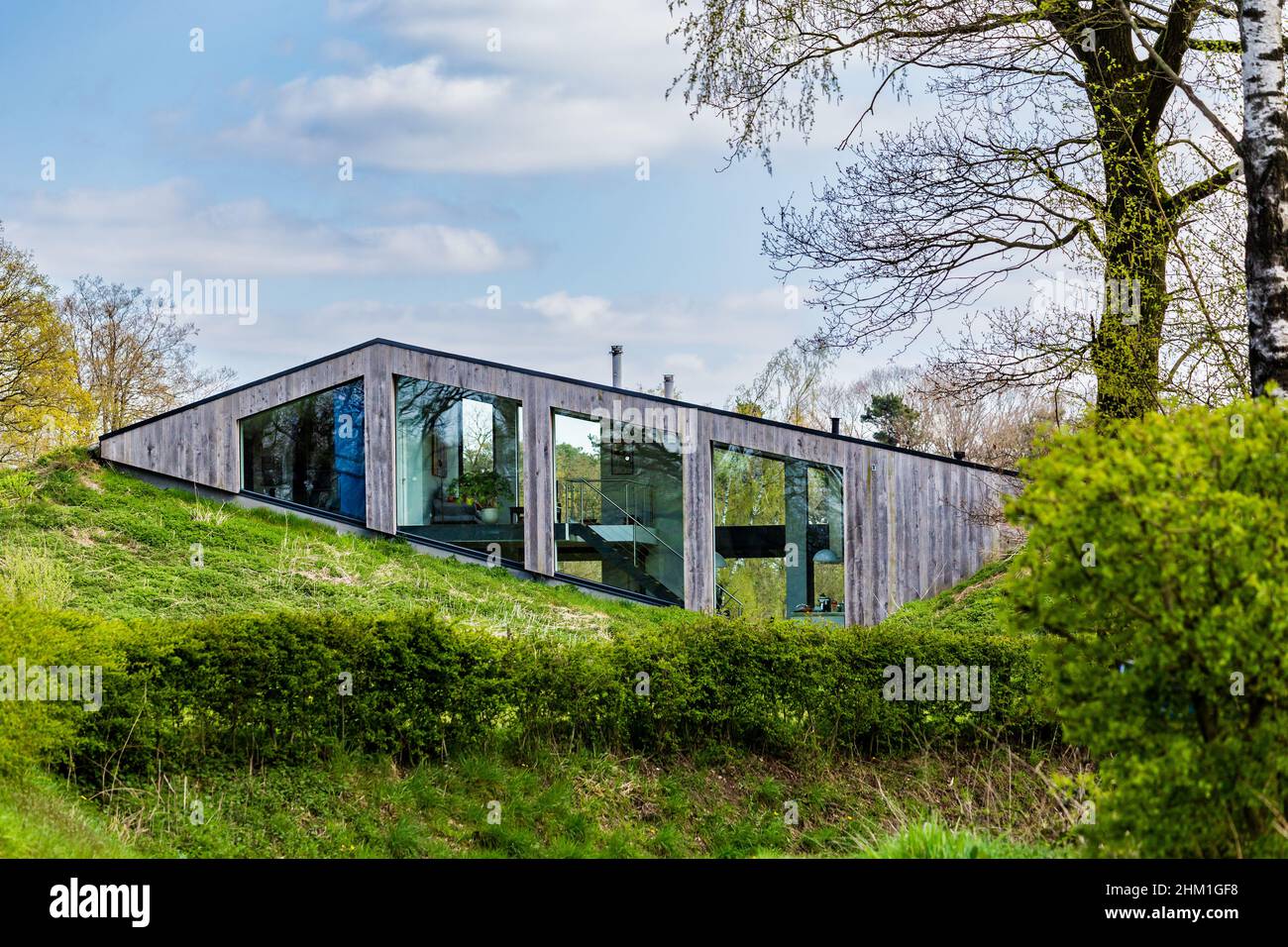 Diepenheim, Paesi Bassi - 25 aprile 2021: Casa moderna sostenibile immersa in una piccola collina il paesaggio in Hof van Twente, Paesi Bassi Foto Stock