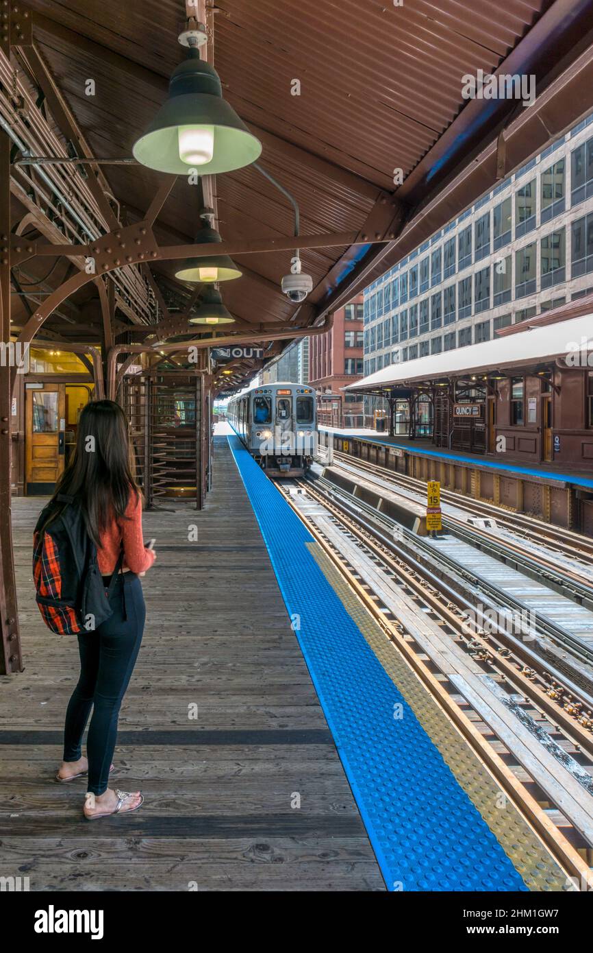 Una persona sul binario della stazione in attesa di un treno Chicago L che arriva alla stazione di Quincy. Foto Stock