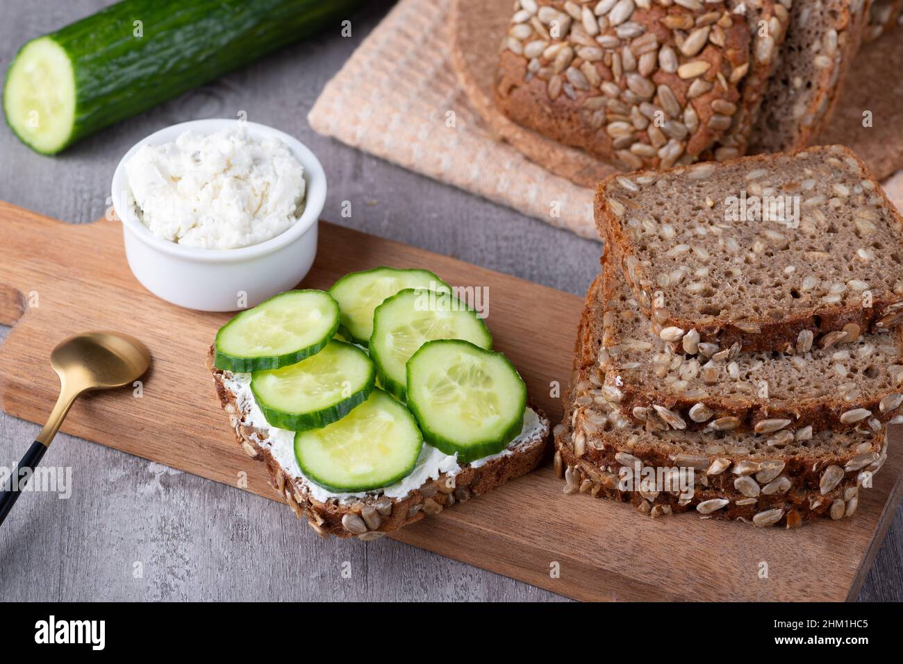 Fette di pane di segale con formaggio casereccio e cetrioli su sfondo grigio Foto Stock