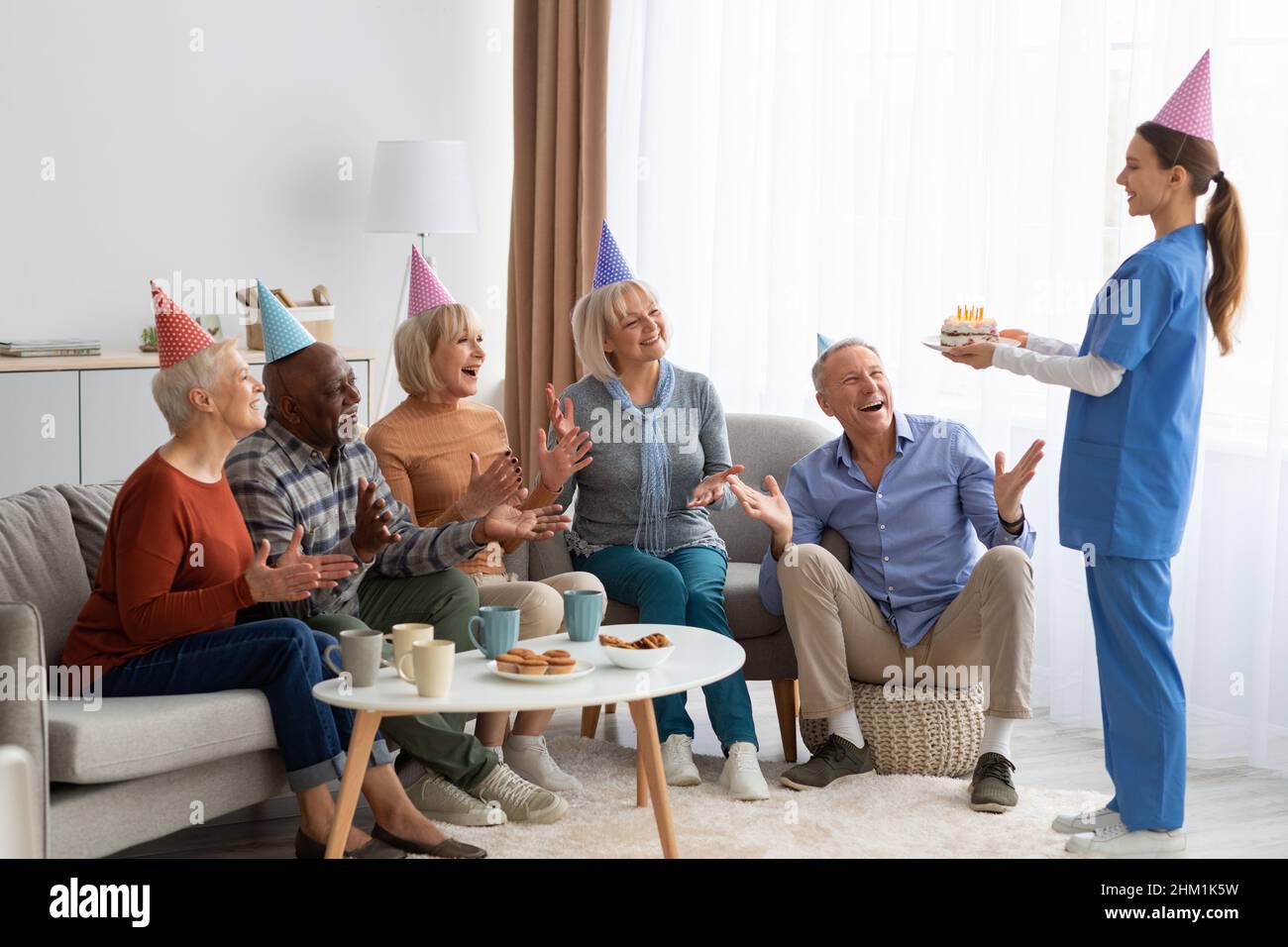 Eccitati anziani che hanno festa di compleanno a casa di cura, panorama Foto Stock